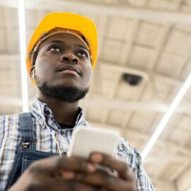 Pensive engineer texting sms at construction site